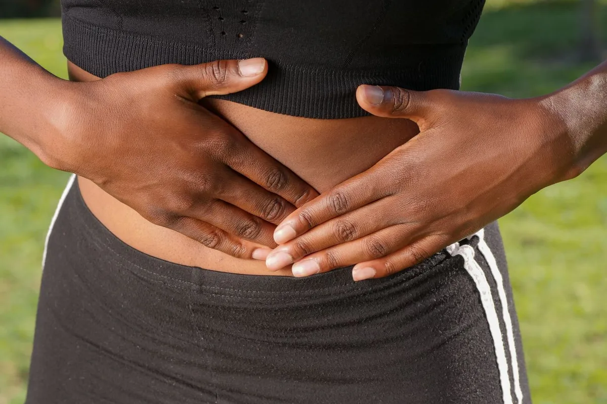 Manos de una persona sujetándose el abdomen por molestias digestivas